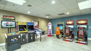 Eine Spielhalle mit verschiedenen Renn- und Arcade-Spielen, darunter ein Pac-Man-Automaten und ein NASCAR-Rennspiel.