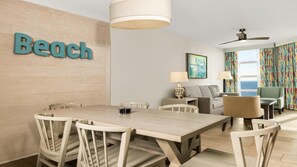 Ein modernes Hotelzimmer mit Essbereich, einer Couch, einer Lampe und Meerblick.