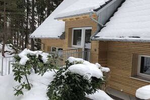 Eine Holzhütte mit einem mit Schnee bedeckten Dach, einem Fenster und einer Tür.