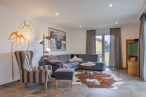 Ein modernes Wohnzimmer mit einer Couch, einem Sessel und einem Kuhfellteppich.