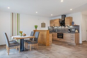 Eine moderne Küche mit Holzausstattung, einem eingebauten Ofen und einem Essbereich mit Tisch und Stühlen.
