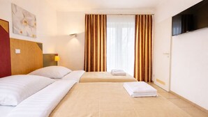 Une chambre d’hôtel avec deux lits, une télévision et une fenêtre avec des rideaux.
