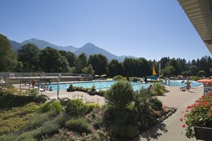 Ein Poolbereich mit mehreren Pools, umgeben von Grünflächen und Bergen im Hintergrund.