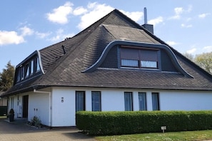 Ein eingeschossiges Haus mit einem geneigten Dach, einem Schornstein und der Hausnummer 8.
