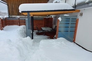 A covered outdoor seating area with a table and chairs, surrounded by snow. - Holiday apartment with 2 bedrooms (Rickenbach)