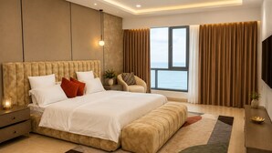Un dormitorio moderno con una cama grande, una mesita de noche, una silla, un televisor y vistas al mar.