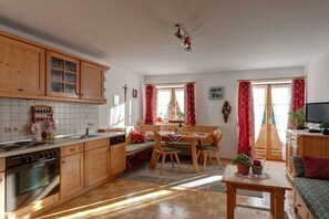 Eine Küche mit Holzausstattung, einem Esstisch mit Stühlen, einer Couch und einem Fernseher.