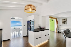 Eine moderne Küche mit Kochinsel, ein Essbereich mit Aussicht und ein Wohnzimmer mit Klavier.