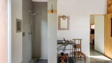 A bathroom with a shower, sink, and wooden chair.