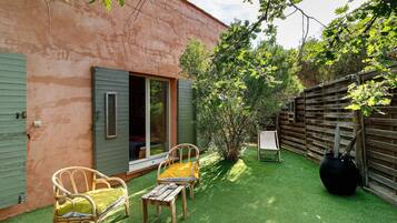 Un patio con una silla y una mesa, cerca de una valla de madera y un edificio con una puerta verde.