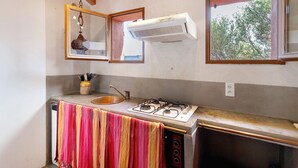 Eine Küche mit Gasherd, Spüle, Fenster und Deckenventilator.