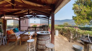 Eine Terrasse im Freien mit Holzmöbeln, einem Fass und einem Grill.