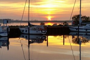 Ein Yachthafen mit vertäuten Booten, ruhigem Wasser und einem Sonnenuntergang im Hintergrund.