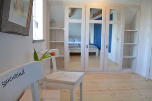 Ein Zimmer mit einem weißen Stuhl, einem kleinen Tisch und einem Schrank mit Spiegelüren.