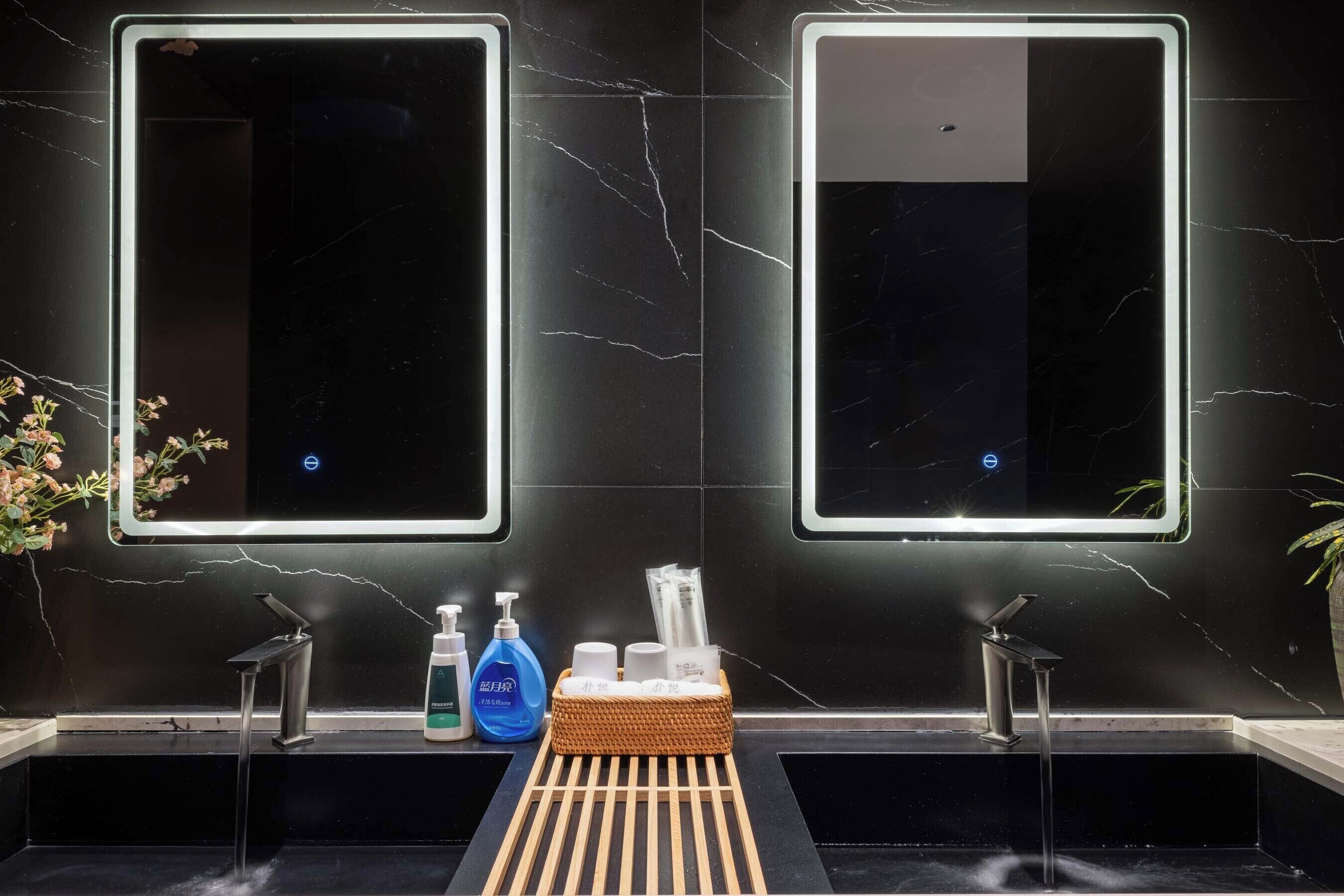 A bathroom with two mirrors, a sink, and a wooden tray.
