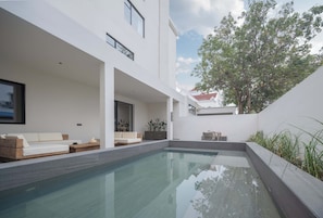 A modern pool area with a glass barrier, a wooden deck, and a white building with large windows. - Silver Beach Puyue Designer Homestay (Beihai)
