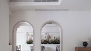 A modern interior with a sofa, a table with candles, and a view through an archway to a dining area. - Silver Beach Puyue Designer Homestay (Beihai)
