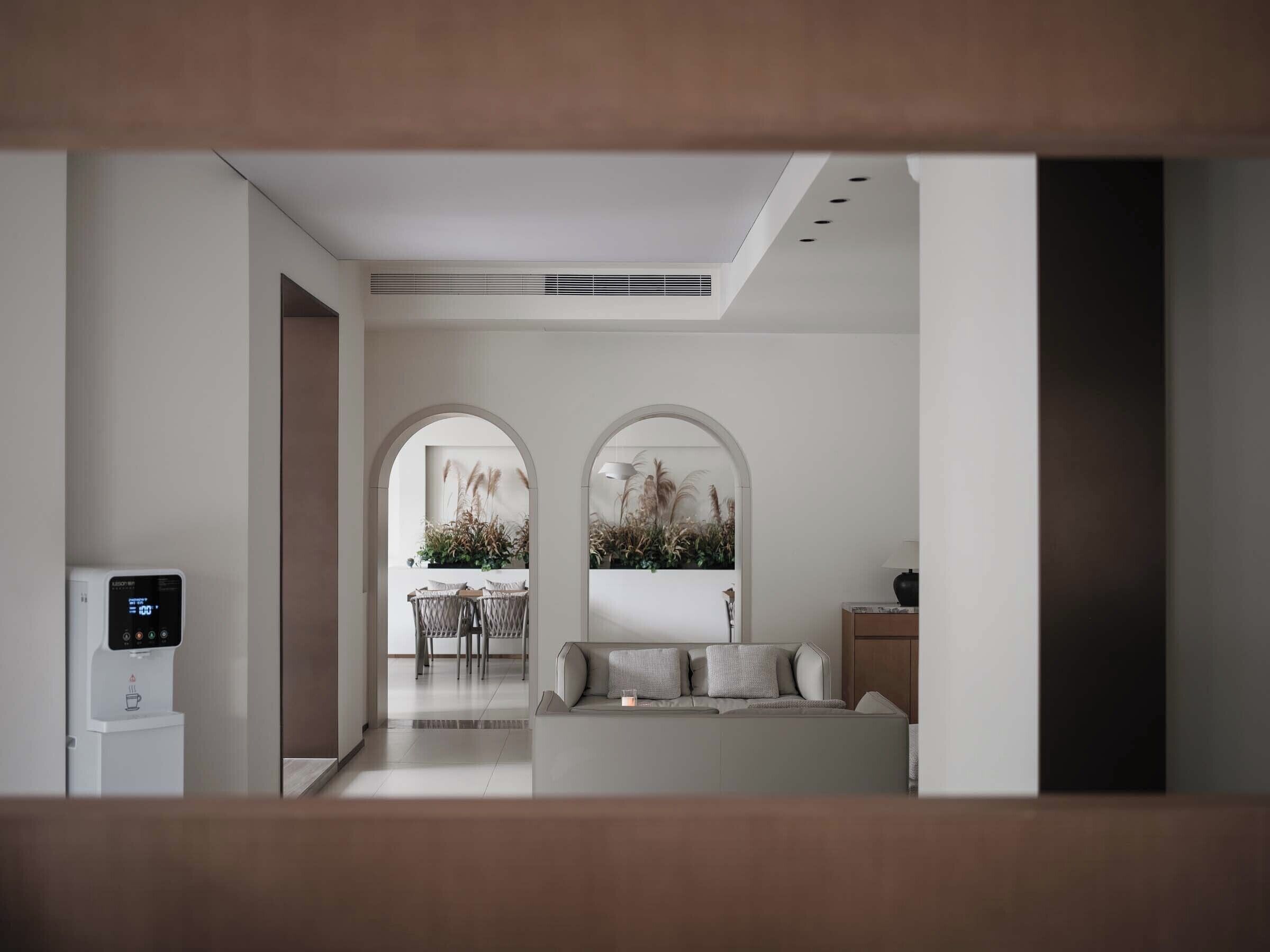 A modern interior with a coffee machine, a sofa, and a dining area with plants.