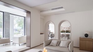 Una sala de estar moderna con un sofá, una mesa baja con velas y vistas a un comedor a través de un arco.