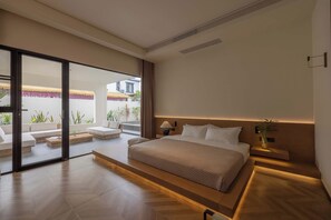 Un dormitorio moderno con una cama grande, una puerta corrediza de vidrio que da a un área de estar exterior y una mesita de noche con lámpara.