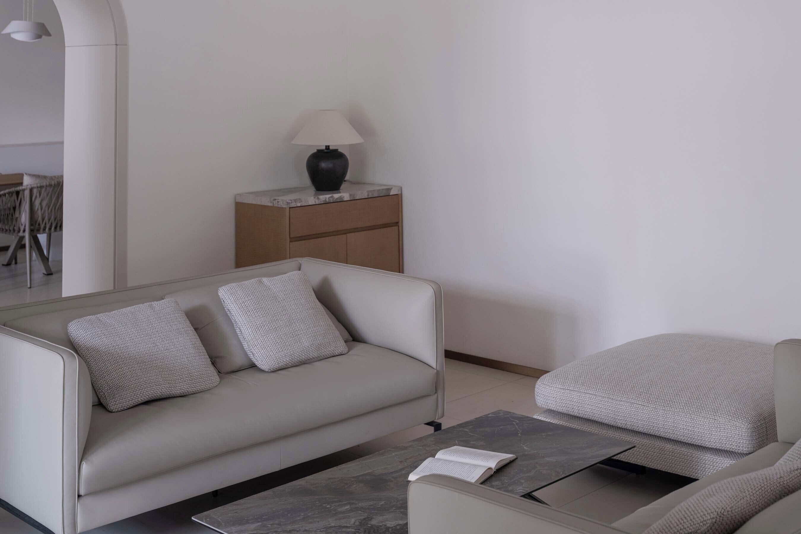 A modern living room with a sofa, a coffee table, a lamp, and a side table.