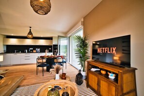 Un soggiorno moderno con televisione, zona pranzo e cucina.