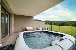 Een bubbelbad op een balkon met uitzicht op een groen landschap.