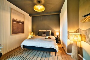 Een slaapkamer met een bed, nachtlampjes, een hanglamp en een wandlamp.
