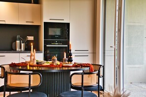 Een moderne keuken met een eettafel voor twee personen, met een inbouwoven en een glazen deur.