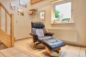 Ein Zimmer mit Massagegerät, einer Holztreppe und einem Fenster mit Blick auf Grünflächen.