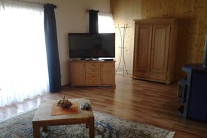 Ein Wohnzimmer mit Fernseher auf einer Holzkommode, einem Couchtisch mit einem dekorativen Gegenstand und einem Kleiderschrank.
