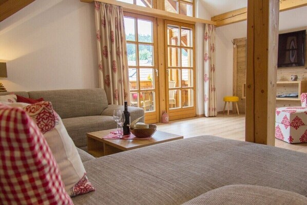 Ein gemütliches Wohnzimmer mit einer Couch, einem Couchtisch und einem Fenster mit Vorhängen.