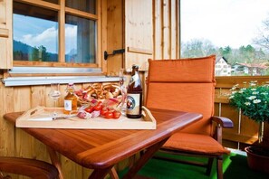 Ein Holztisch mit einem Tablett mit Speisen und Getränken, ein Stuhl und ein Fenster mit Blick auf Häuser.