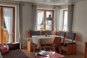 Ein Essbereich mit Tisch, Stühlen und Blick durch die Fenster.