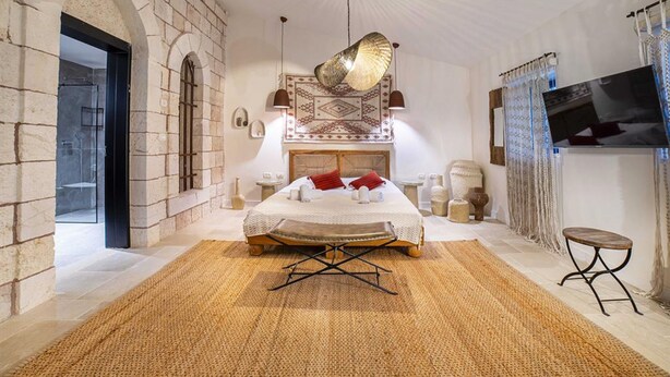 Ein geräumiges Schlafzimmer mit einem großen Bett, einem Fernseher und einer Steinwand.