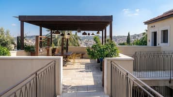 A rooftop terrace with a pergola, outdoor furniture, and a view of the cityscape.