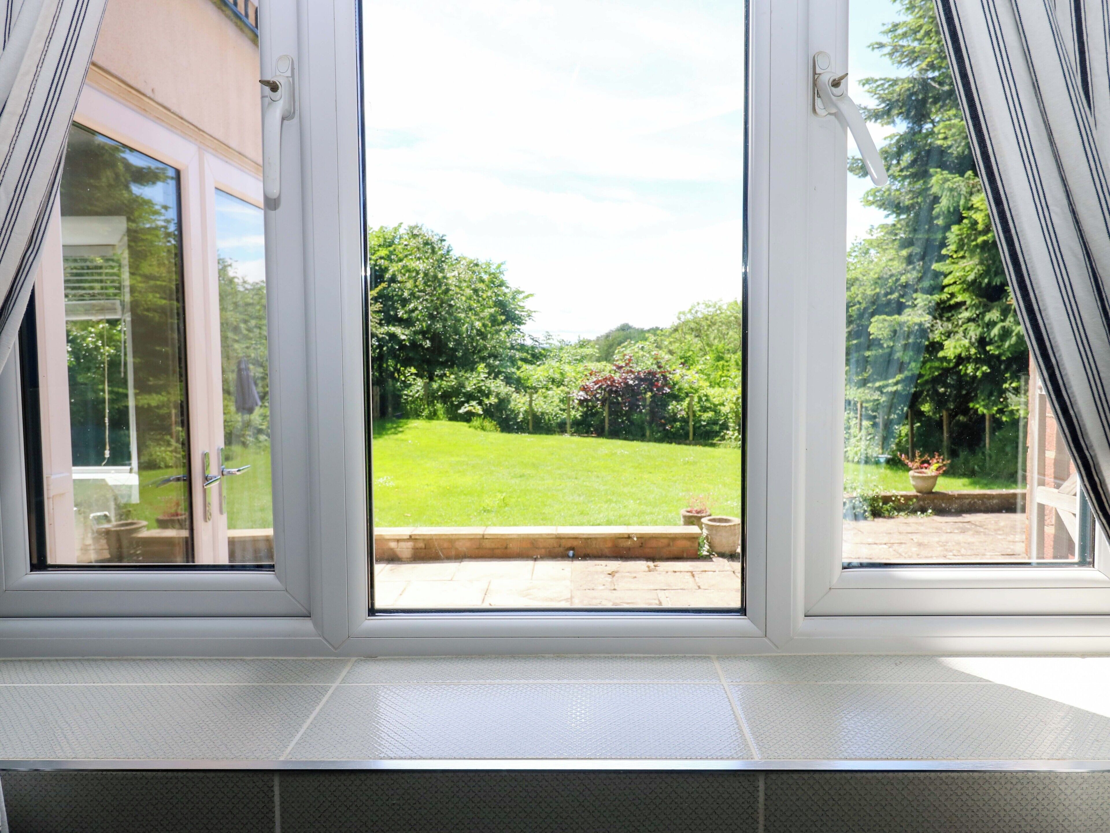 A window with a view of a well-maintained garden and a brick pathway.
