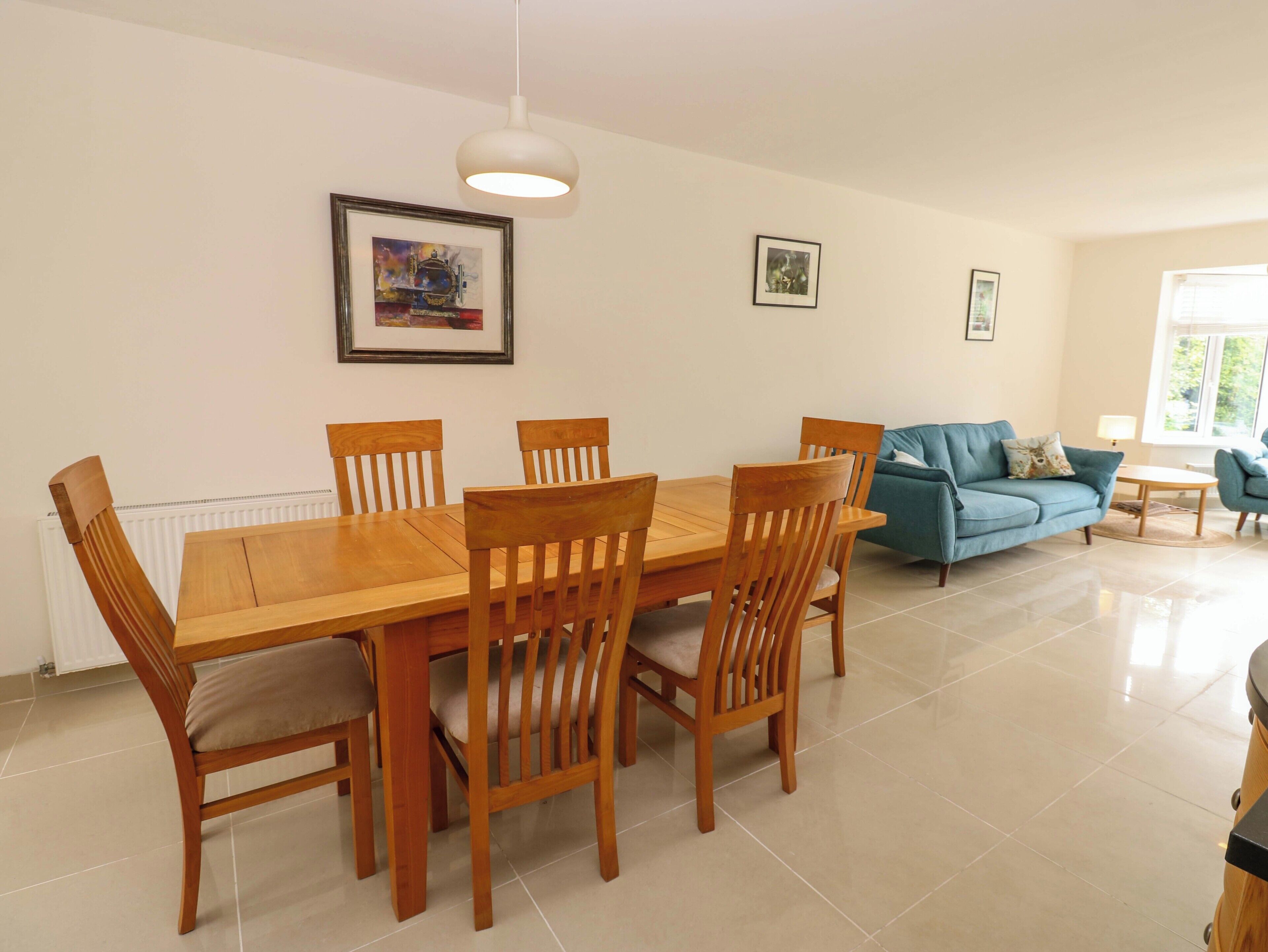 A dining area with a wooden table and chairs, a blue sofa, and framed artwork on the walls.
