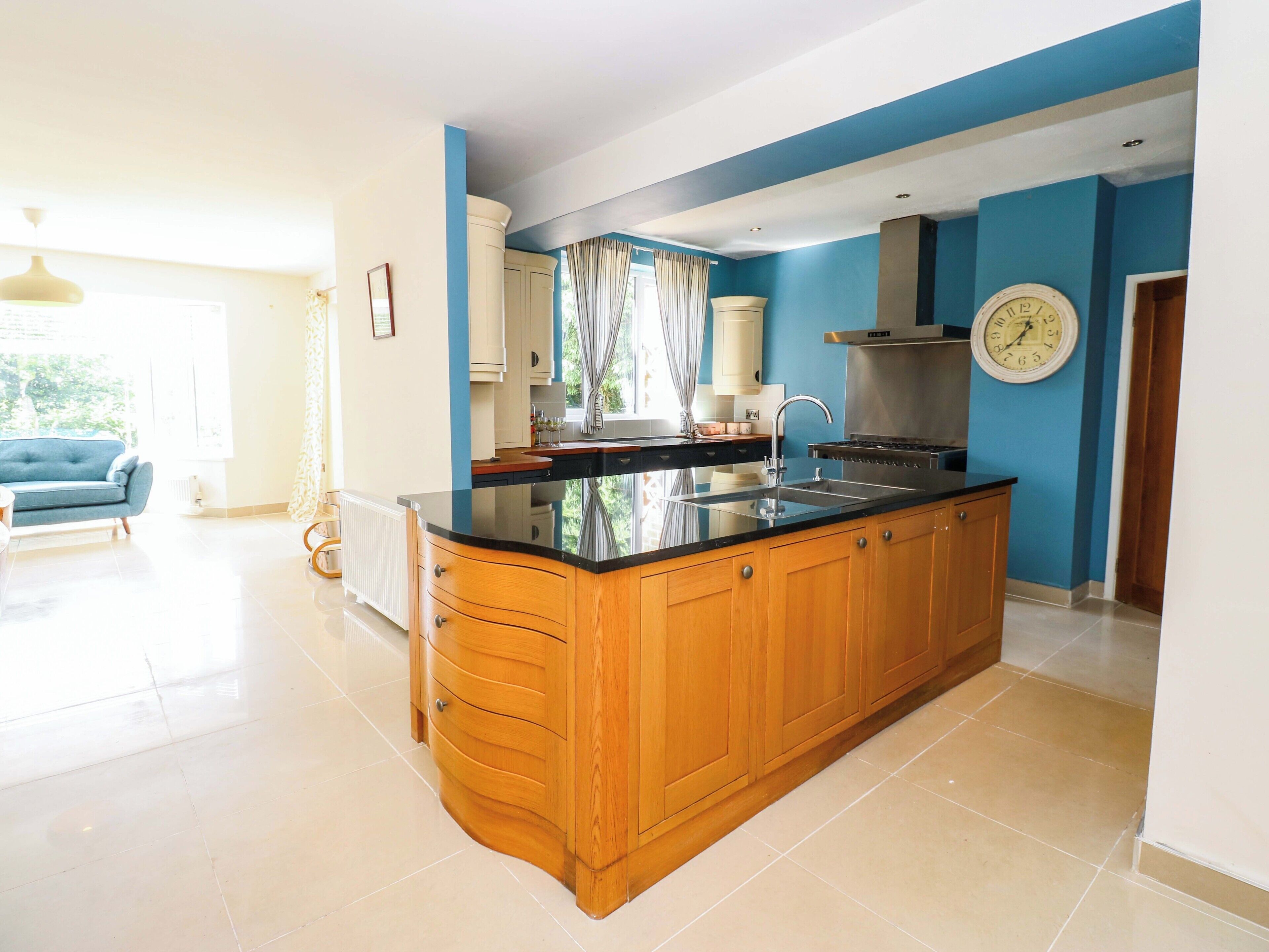 A modern kitchen with wooden cabinets, a black countertop, and a stainless steel range hood.