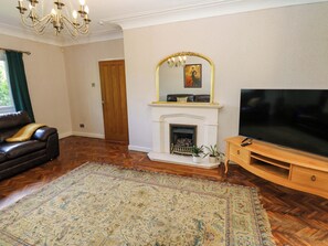 A living room with a fireplace, a television, a sofa, and a patterned rug. - 331 Coniscliffe Road (Darlington)