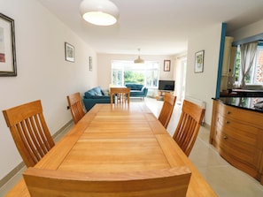A dining area with a wooden table and chairs, a sofa, and a kitchen area with cabinets and a countertop. - 331 Coniscliffe Road (Darlington)