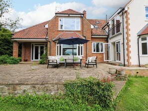 A two-story house with a patio, brick exterior, and a covered seating area with a table and chairs. - 331 Coniscliffe Road (Darlington)