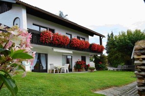 Ein zweistöckiges Gebäude mit Balkon, Rasen und Außenbestuhlung.