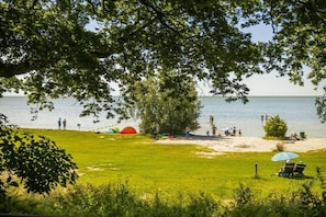 Ein Strand mit Zelten, einer Rasenfläche und Blick aufs Wasser.