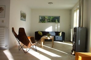 Ein Wohnzimmer mit einer Couch, einem Couchtisch, einem Sessel und einem Fernseher.