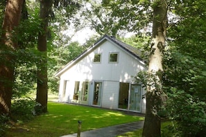 Ein weißes Haus mit einem Giebeldach, großen Fenstern und einer Veranda.
