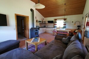 A cozy living room with a sofa, a coffee table, and a fireplace. - Holiday home with 2 bedrooms (Neuschönau)