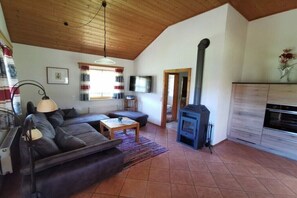 A cozy living room with a sofa, coffee table, and a fireplace. - Holiday home with 2 bedrooms (Neuschönau)