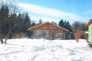 A wooden cabin with a sloped roof, surrounded by snow-covered ground and trees. - Holiday home with 2 bedrooms (Neuschönau)