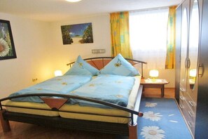 Ein Schlafzimmer mit einem Bett, zwei Nachttischlampen, einem Nachttisch, einem Kleiderschrank und einem Fenster mit Vorhängen.